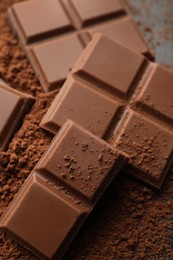 Delicious milk chocolate and cocoa powder on grey table, closeup