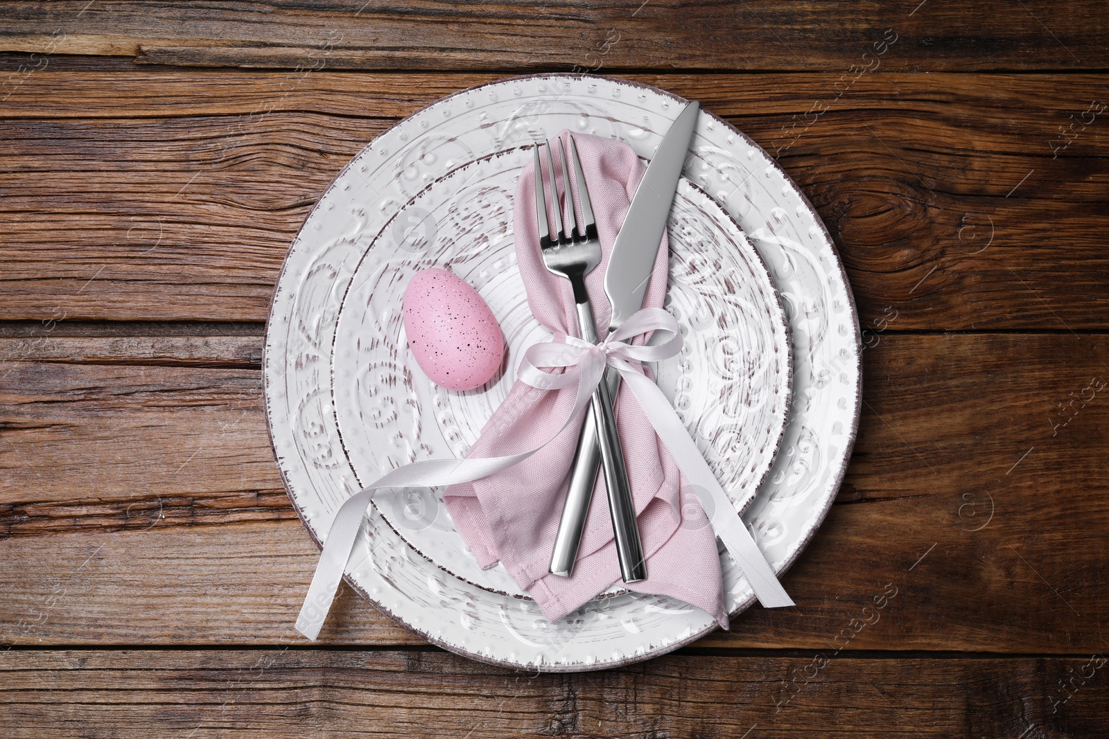 Photo of Festive table setting with painted egg and cutlery, top view. Easter celebration