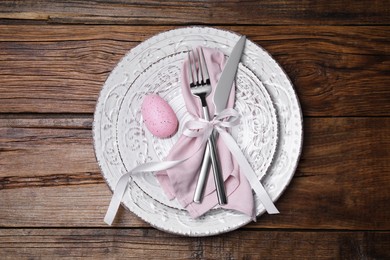 Photo of Festive table setting with painted egg and cutlery, top view. Easter celebration
