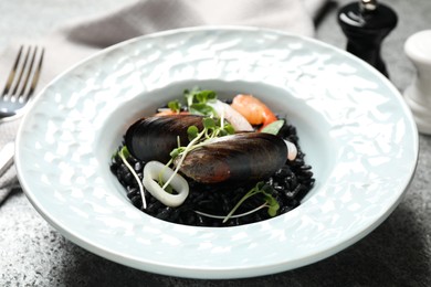 Photo of Delicious black risotto with seafood on grey table, closeup