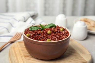 Photo of Bowl with delicious cooked brown rice on table indoors