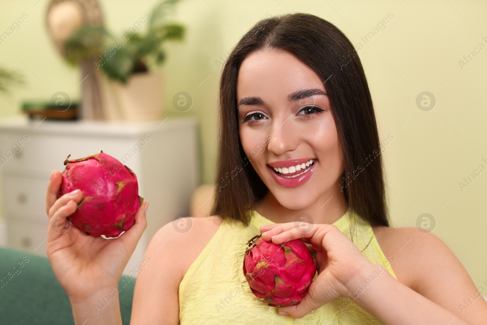 Photo of Young woman with fresh pitahayas at home. Exotic fruits