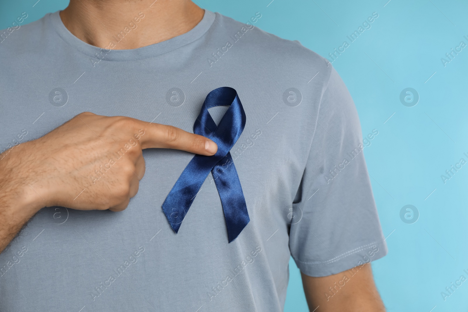 Photo of Man with ribbon on light blue background, closeup. Urology cancer awareness