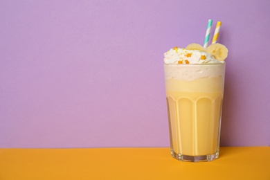 Glass of tasty milk shake and space for text on color background