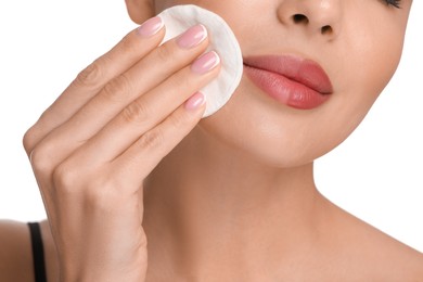 Beautiful woman removing makeup with cotton pad on white background, closeup