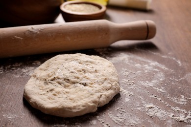 Fresh dough and rolling pin on wooden table. Cooking grissini