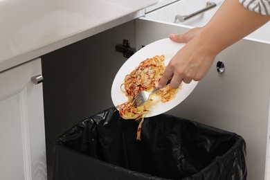 Woman throwing pasta into bin indoors, closeup