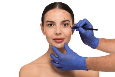 Doctor with pencil preparing patient for cosmetic surgery operation on white background
