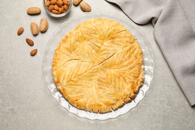 Photo of Traditional galette des rois and almonds on light grey table, flat lay