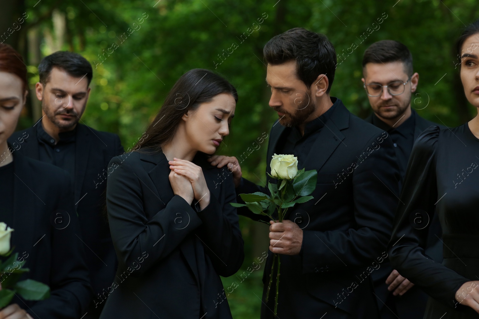 Photo of Funeral ceremony. Sad people in black clothes mourning outdoors