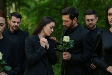 Funeral ceremony. Sad people in black clothes mourning outdoors