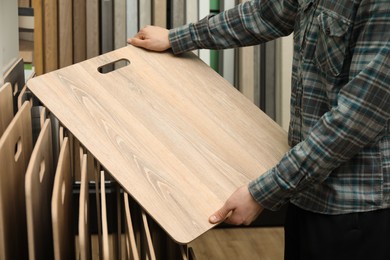 Photo of Man with sample of wooden flooring in shop, closeup