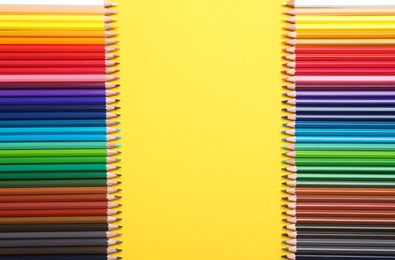 Photo of Color pencils on yellow background, flat lay. Space for text