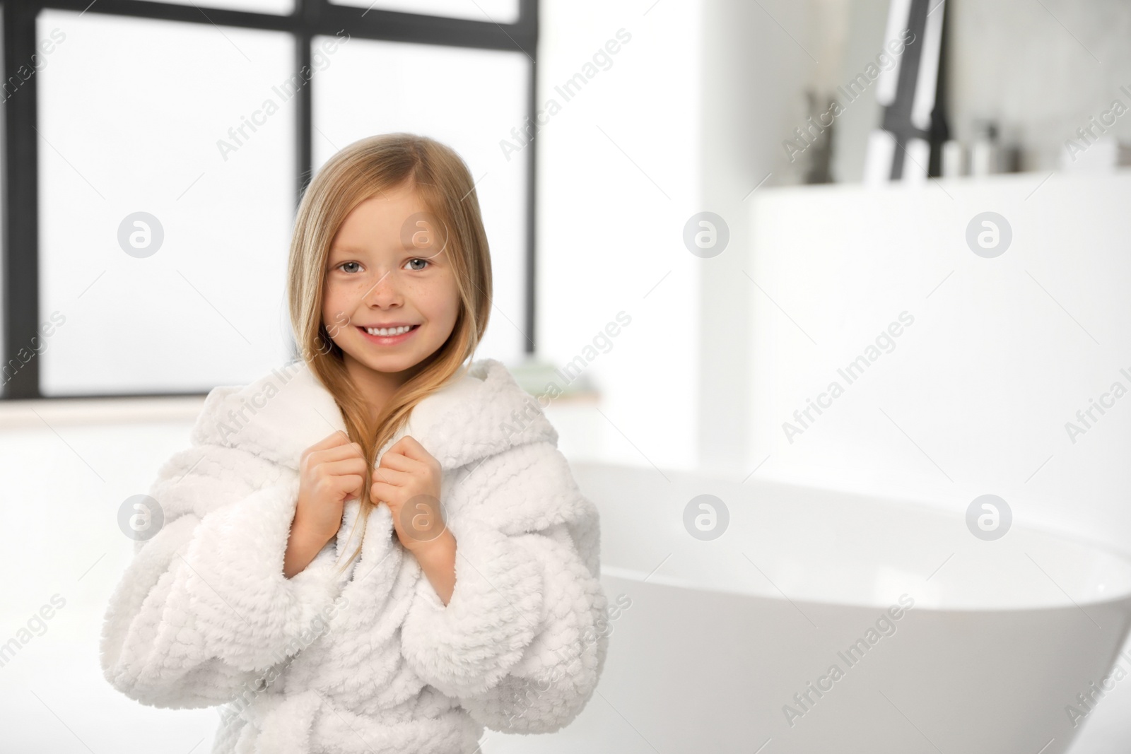 Photo of Cute little girl in bathroom. Space for text
