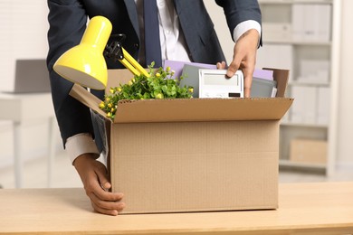 Unemployment problem. Man with box of personal belongings at table in office, closeup