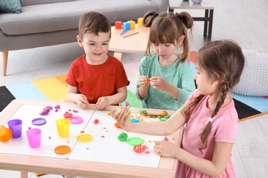 Photo of Cute little children using play dough at table indoors