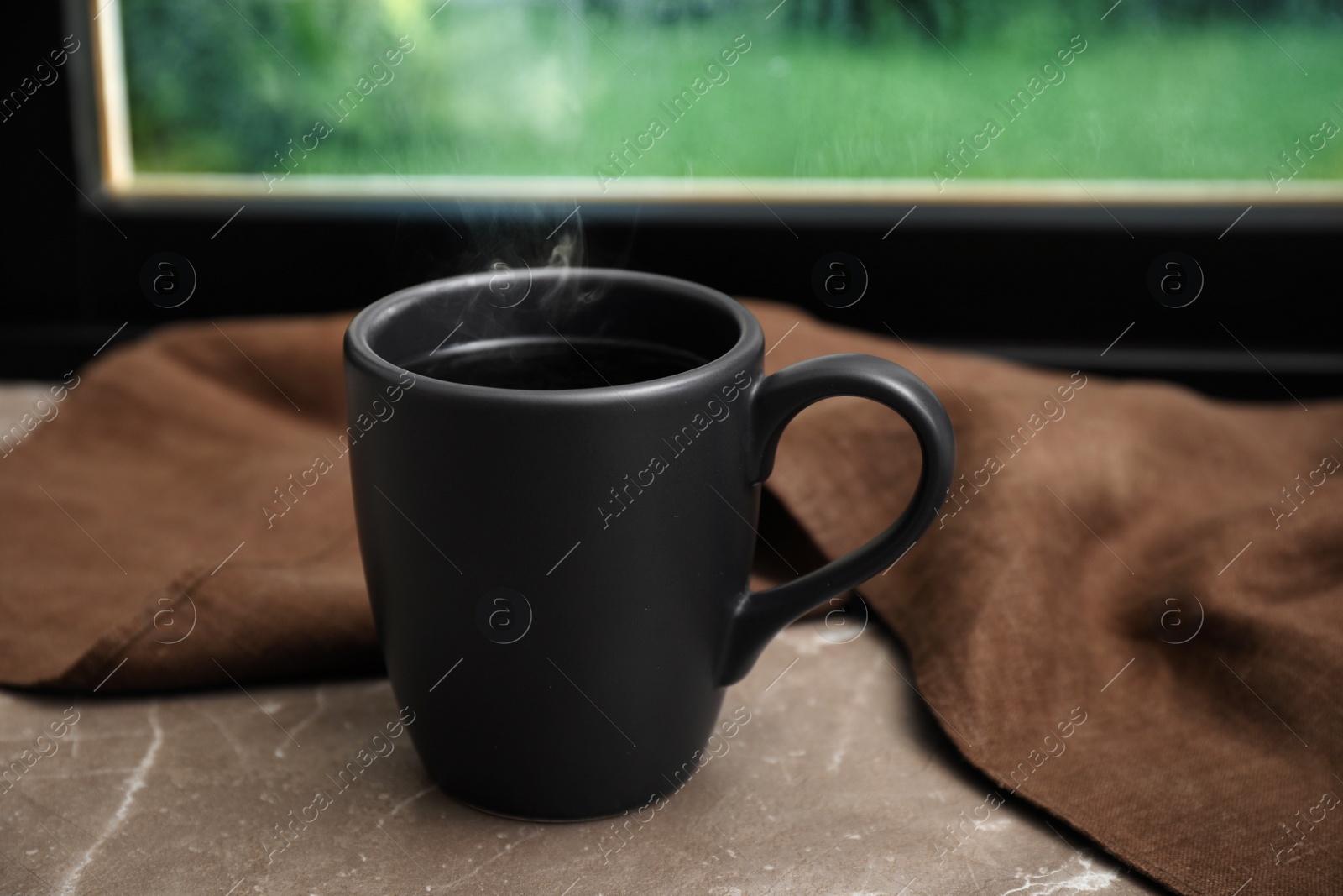 Photo of Cup of hot beverage on grey marble windowsill