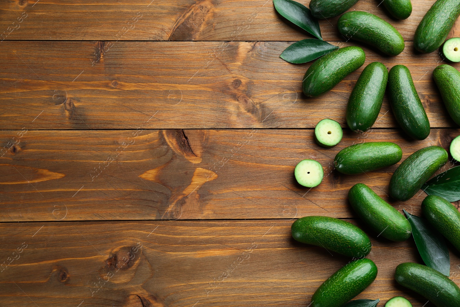 Photo of Fresh seedless avocados with green leaves on wooden table, flat lay. Space for text