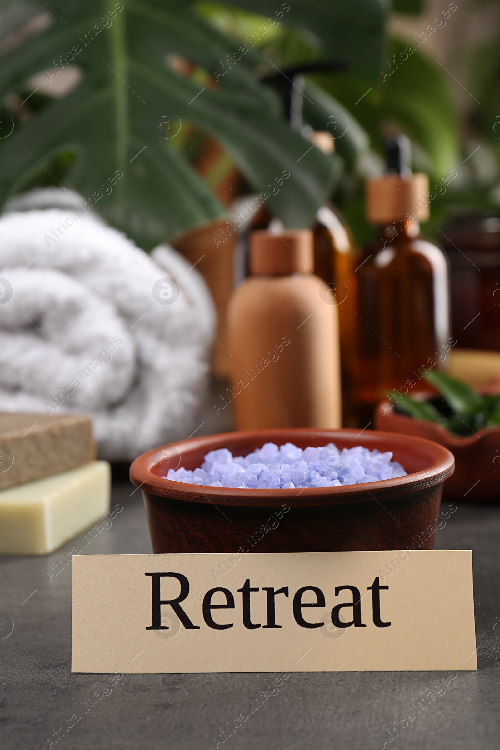 Photo of Card with word Retreat and bowl of sea salt on grey table. Space for text