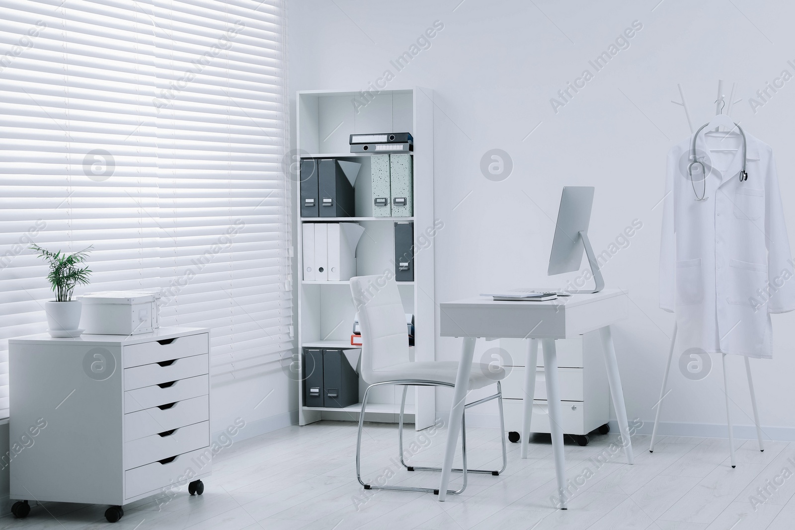 Photo of White doctor's gown and stethoscope hanging on rack in clinic