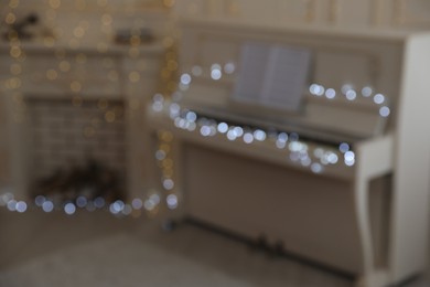 Photo of Blurred view of white piano with festive decor indoors. Christmas music