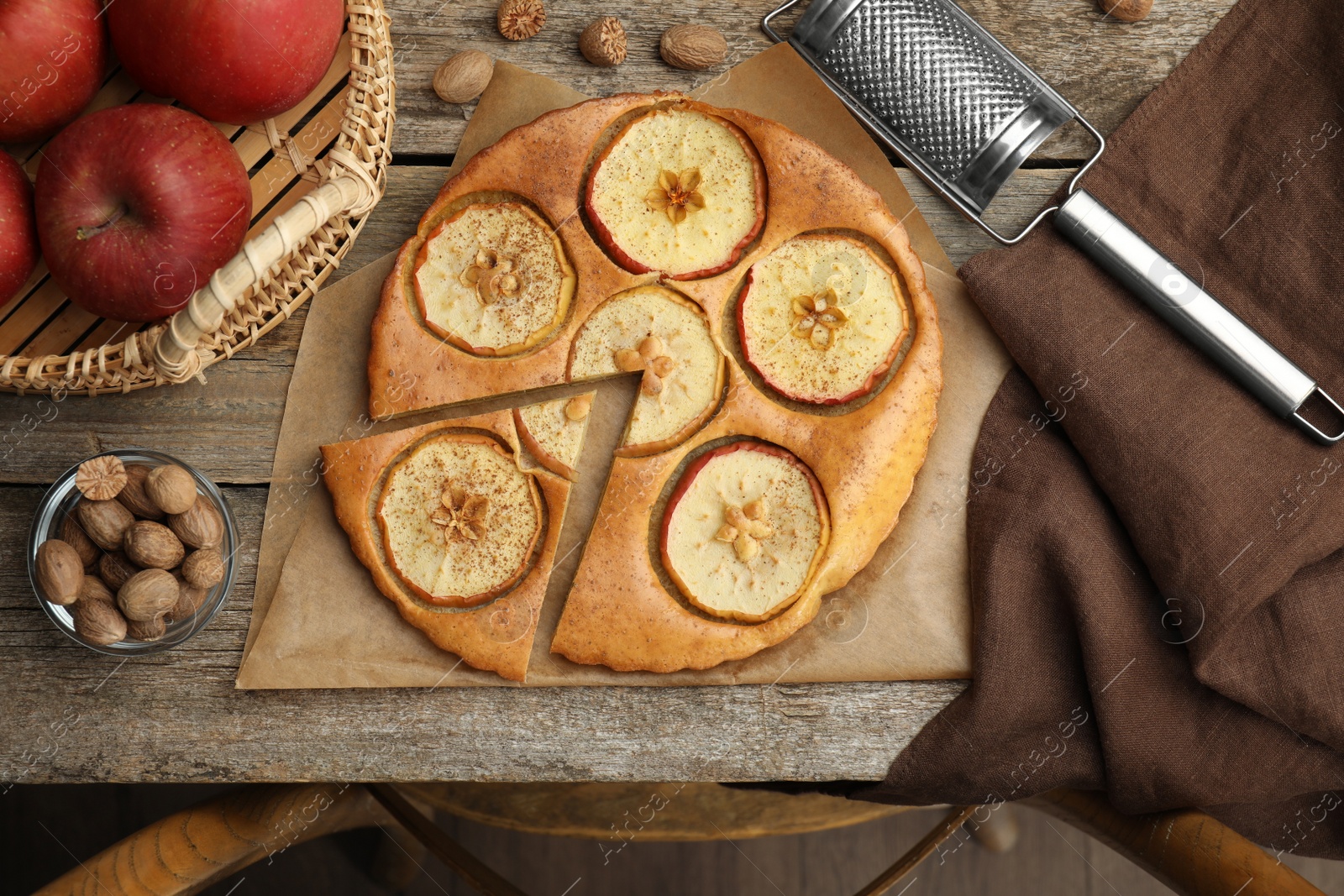 Photo of Tasty apple pie, nutmeg powder, seeds and fresh fruits on wooden table, flat lay