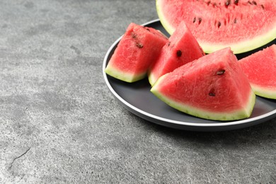 Photo of Delicious fresh watermelon slices on grey table. Space for text