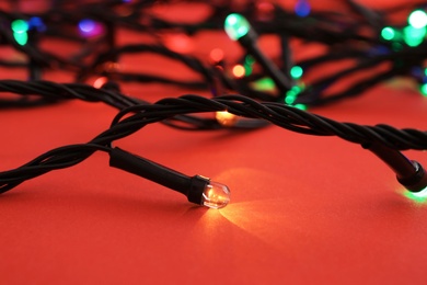 Glowing Christmas lights on color background, closeup