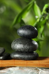 Photo of Stacked stones on bamboo mat over water against blurred background