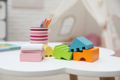 Photo of Bright toys, pencils and book on white table in playroom