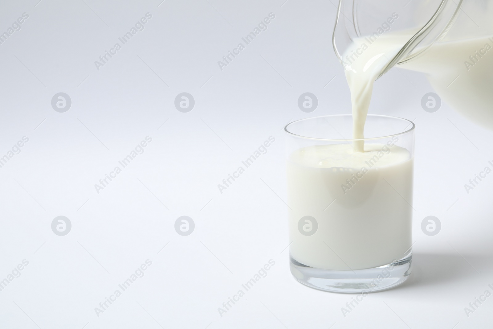 Photo of Pouring milk into glass on white background