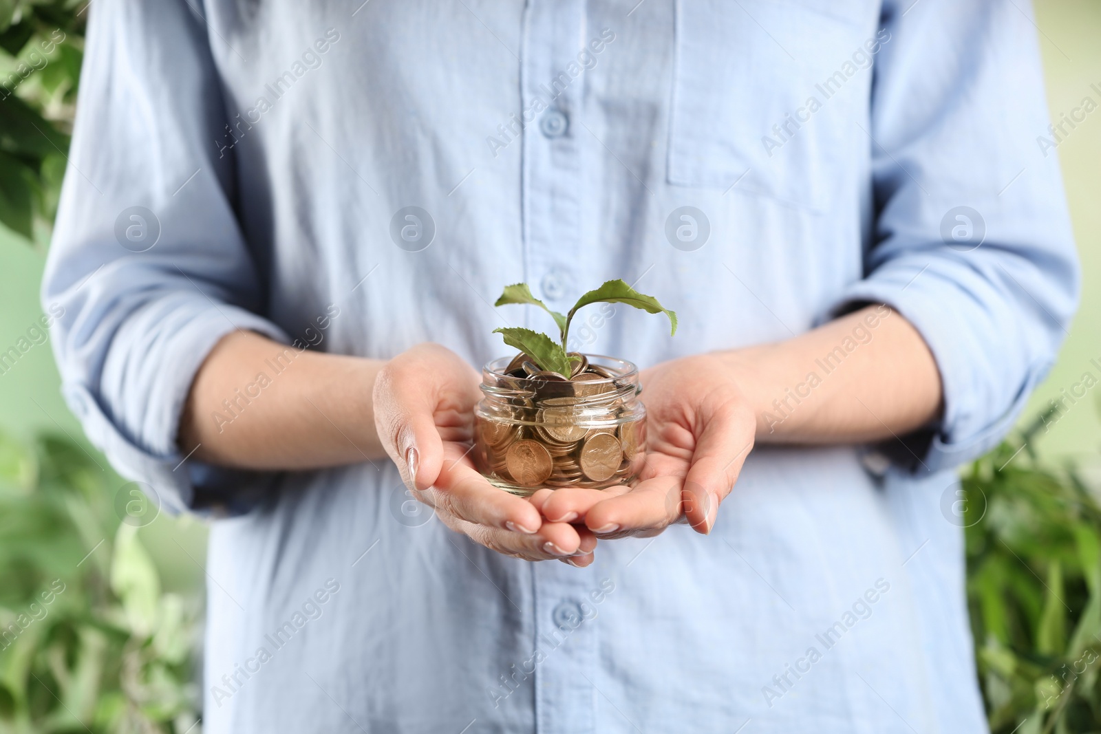 Photo of Woman holding coins and green sprout, closeup. Money savings