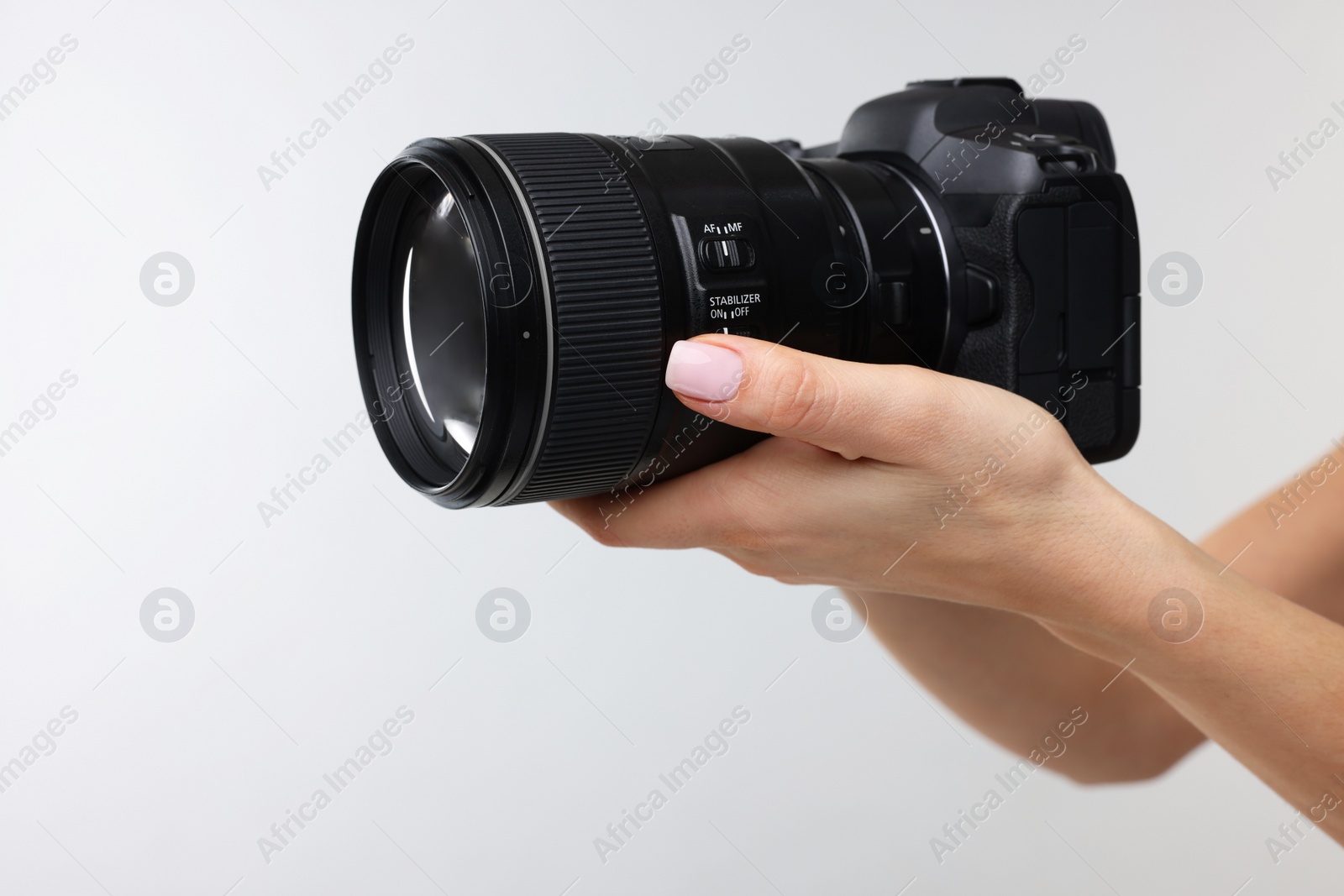 Photo of Photographer with camera on light grey background, closeup