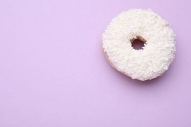 Photo of Tasty donut with coconut shavings on purple background, top view. Space for text