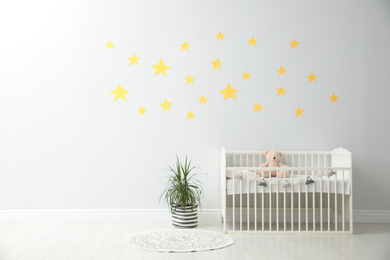 Photo of Minimalist room interior with baby crib and decor elements. Space for text