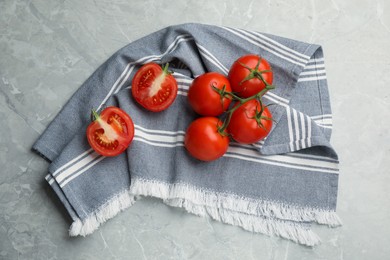 Photo of Kitchen towel and fresh tomatoes on grey table, flat lay