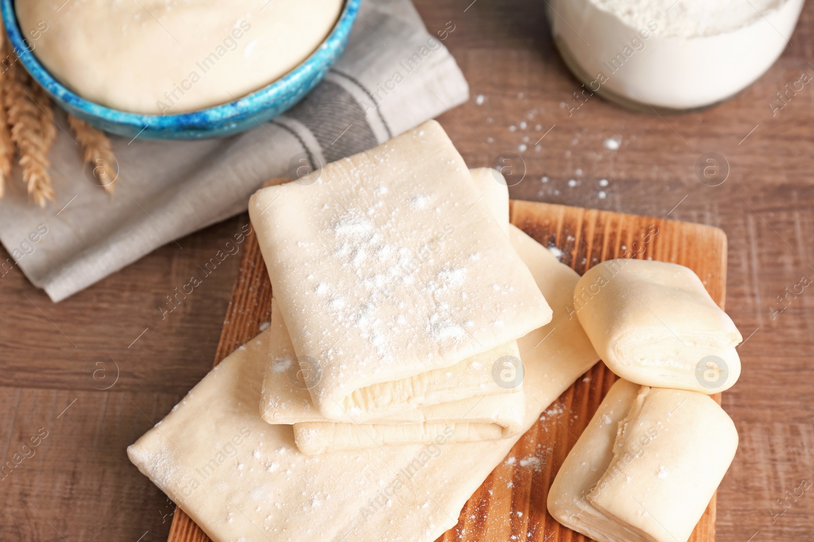 Photo of Fresh raw dough on wooden board, closeup