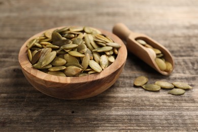 Bowl and scoop with peeled pumpkin seeds on wooden table