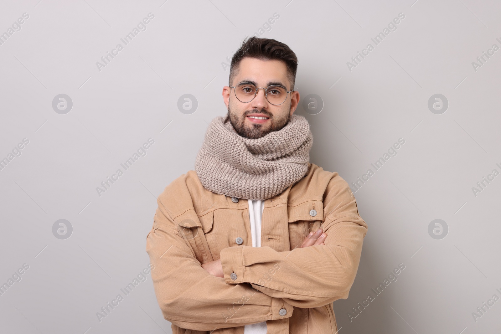 Photo of Smiling man in warm scarf on light grey background