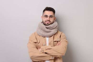 Smiling man in warm scarf on light grey background