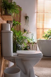 Photo of Stylish bathroom interior with toilet bowl and green plants