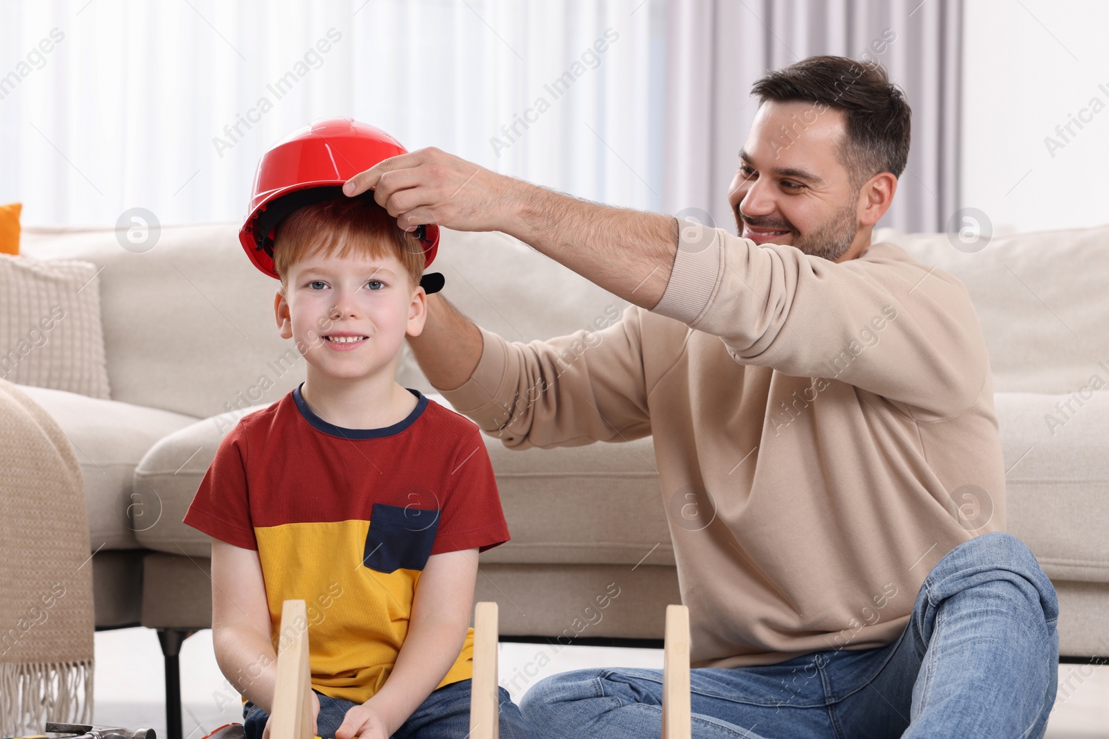 Photo of Father putting hard hat on his son at home. Repair work