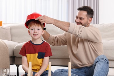 Father putting hard hat on his son at home. Repair work