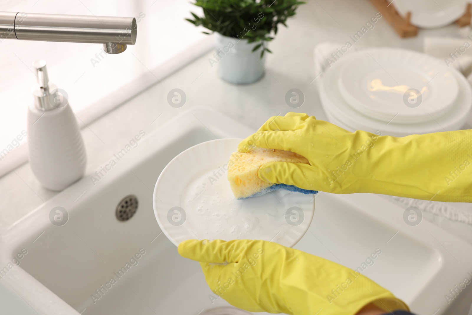 Photo of Woman washing plate at sink in kitchen, closeup