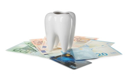 Photo of Ceramic model of tooth, euro banknotes and credit cards on white background. Expensive treatment