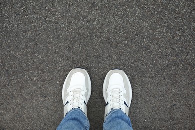 Photo of Man in sneakers standing on asphalt, top view. Space for text