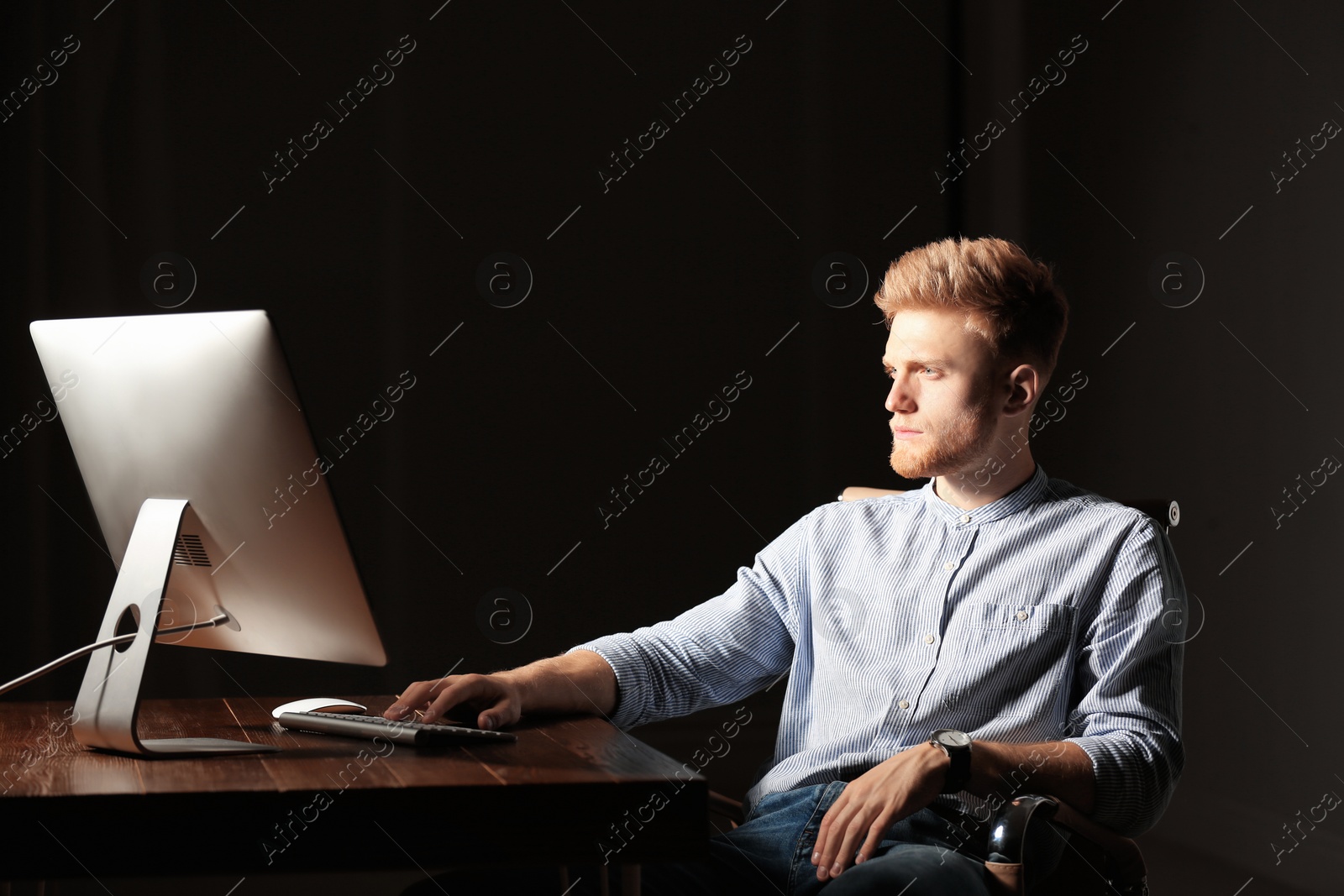 Photo of Concentrated young man working in office alone at night