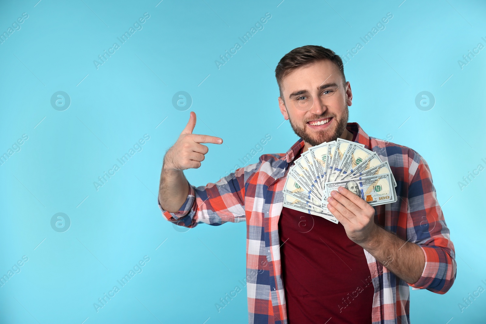 Photo of Portrait of happy young man with money on color background. Space for text