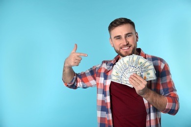 Portrait of happy young man with money on color background. Space for text