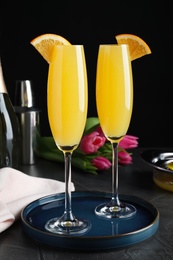 Glasses of Mimosa cocktail with garnish on grey table